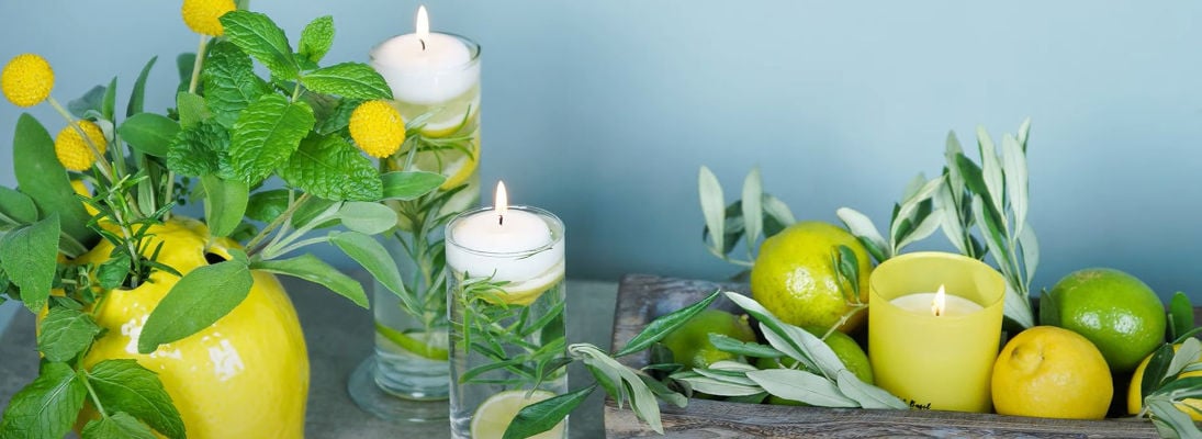 Künstliche Zitronen arrangiert auf einem Holztablett, echtes Zitronengrün, Schwimmkerzen und Duftkerzen mit Zitronenaroma